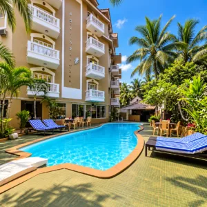 Swimming pool with sun loungers in front of the resort building at Goveia Grand Resort Candolim Goa