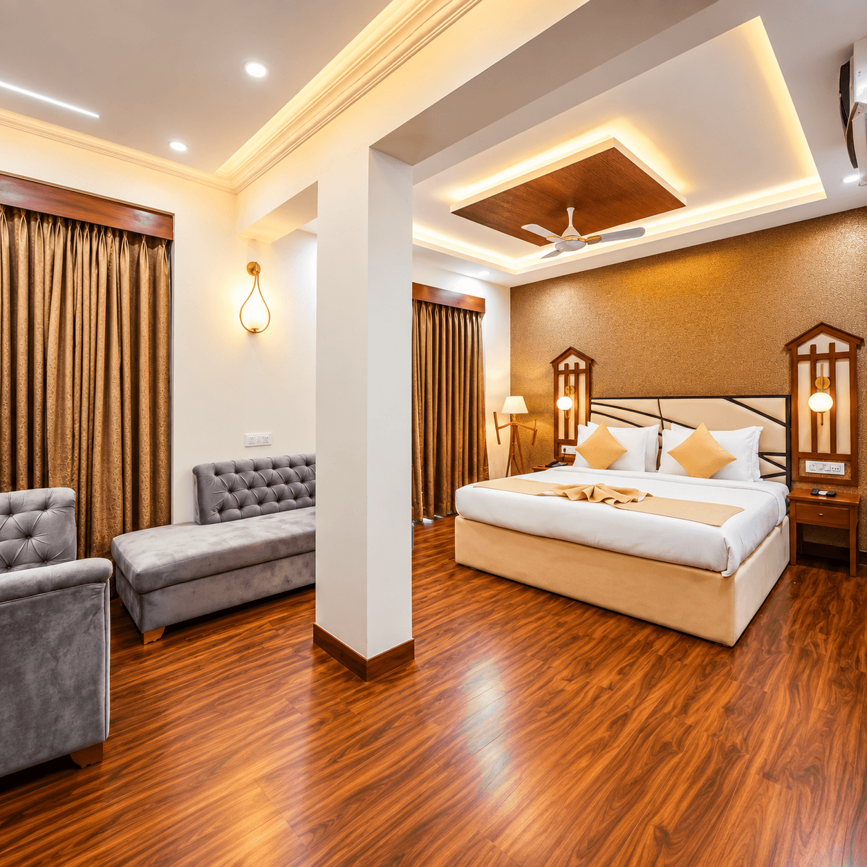 Spacious suite room with sofa, sitting area and wooden floor at Vagator Downtown by WS Goa