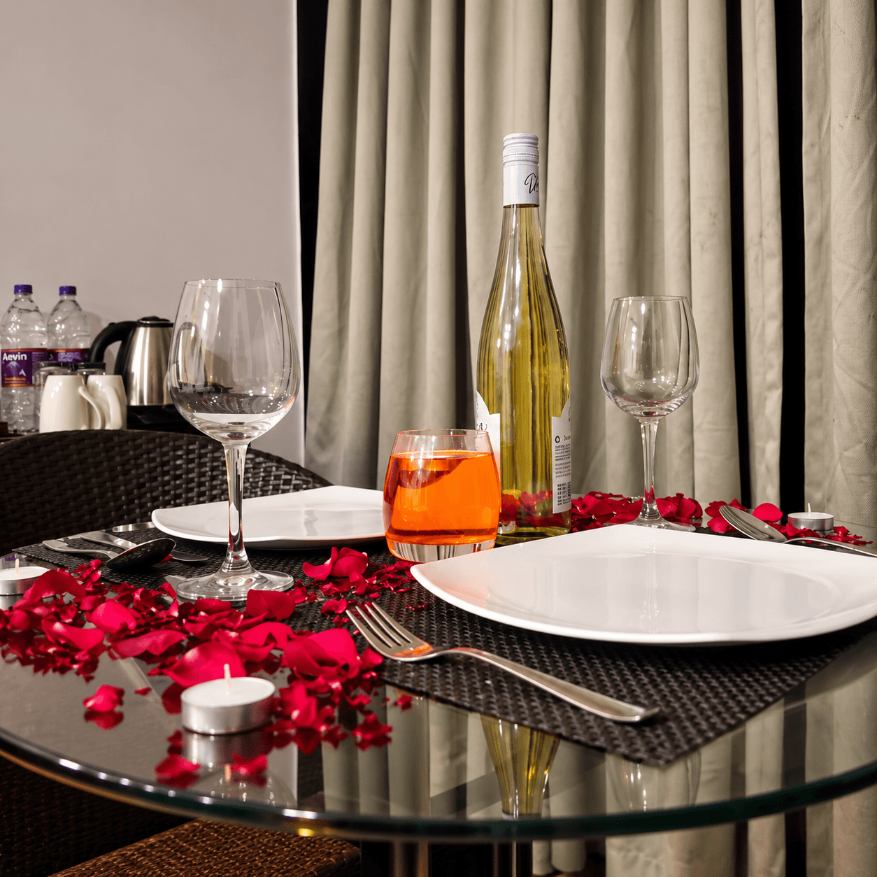 Wine bottle, glasses and candle on romantic dinner table for Goa honeymoon package at Resorte Village Royale