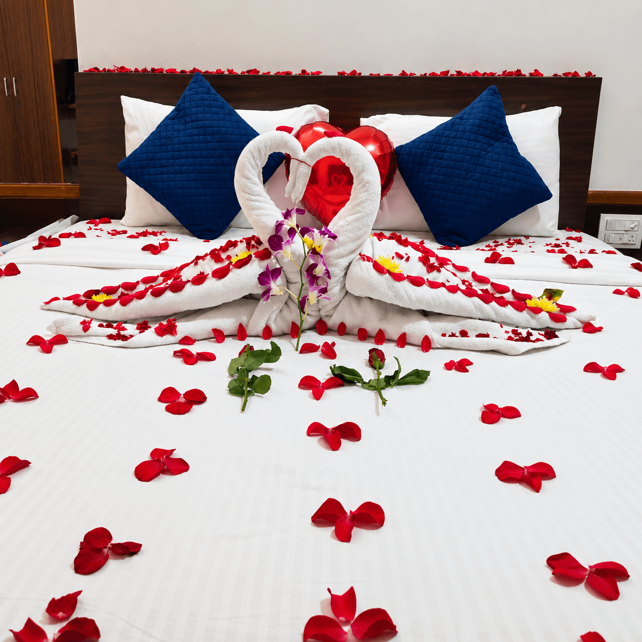 Honeymoon bed decoration with swan towels and rose petals at Resorte Village Royale Goa