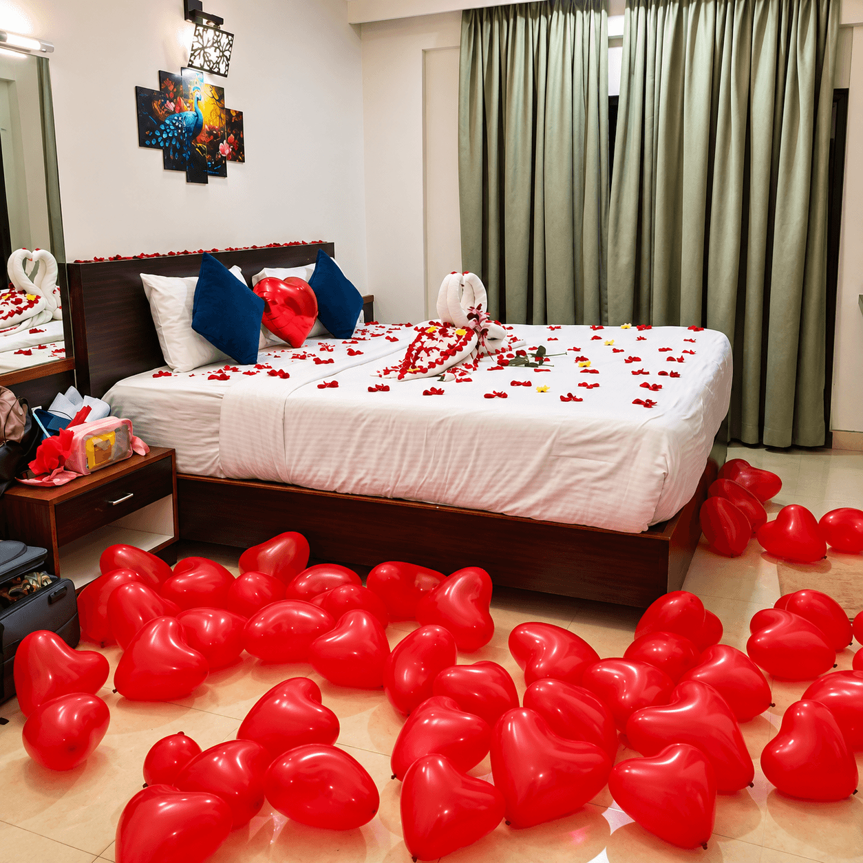 Honeymoon room with red heart balloons on the floor and decorated bed at Resorte Village Royale Goa