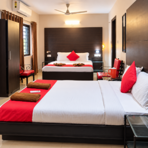 Family room with two beds and red cushions at Rivasa Resort, Calangute Goa