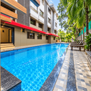 Long outdoor swimming pool with sun loungers and palm trees at Rivasa Resort, Calangute Goa